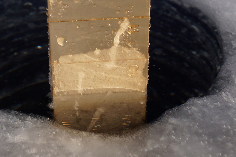 On Sunday, the lake ice was about 9 inches deep on the North end of the lake.  I wanted the metal to shine in the photo, but any wet area on the ruler froze instantly in the 7°F air and blowing wind. After a minute or so dunking the measuring stick below the water to get the ice off only to have it reform a fraction of a second later, I gave up and took this shot. The ice that covers Lucerne is under close to 6.5 inches of frozen snow with a few inexplicable slushy patches between the two layers.